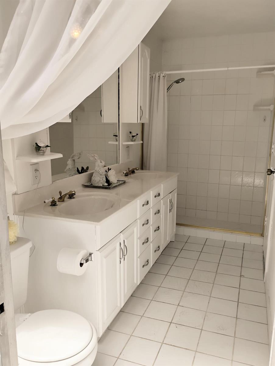 A white bathroom features a double vanity, tiled shower, and white floor tiles — 15531 42nd Road N, FL 33470, FL