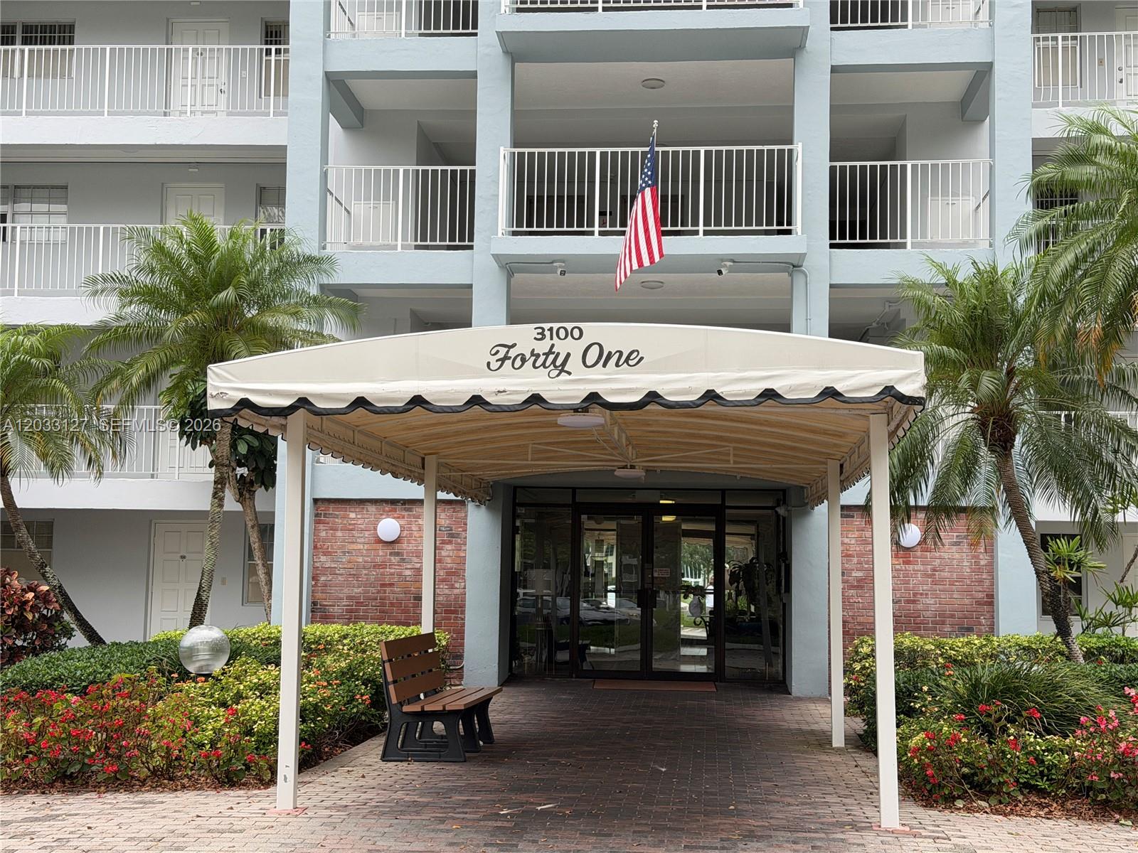 The exterior of a multi-story apartment building features a covered entrance with a fabric awning — 3100 N Course Ln # 208, Pompano Beach FL 33069, POMPANO BEACH, FL