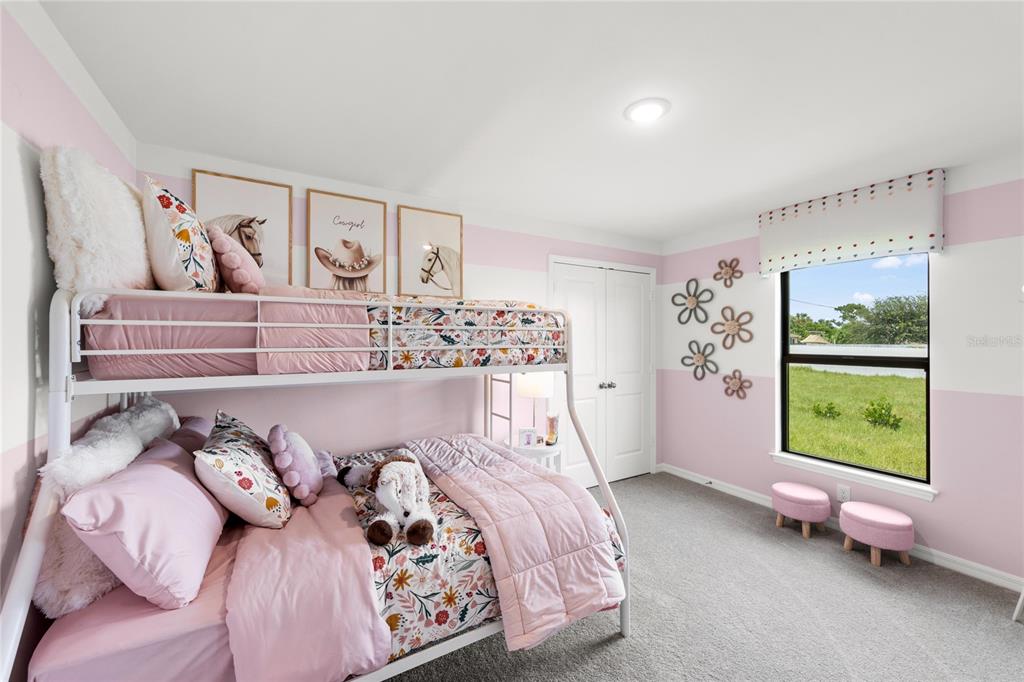 A child's bedroom features a white metal bunk bed, pink wall stripes, and a window — 7608 N PRIMROSE DRIVE, CITRUS SPRINGS, FL