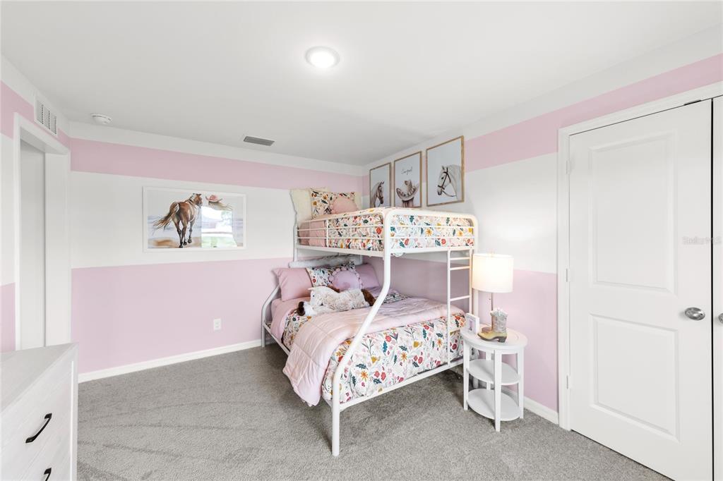 A bedroom features a white bunk bed, pink and white striped walls, and gray carpeting — 7608 N PRIMROSE DRIVE, CITRUS SPRINGS, FL