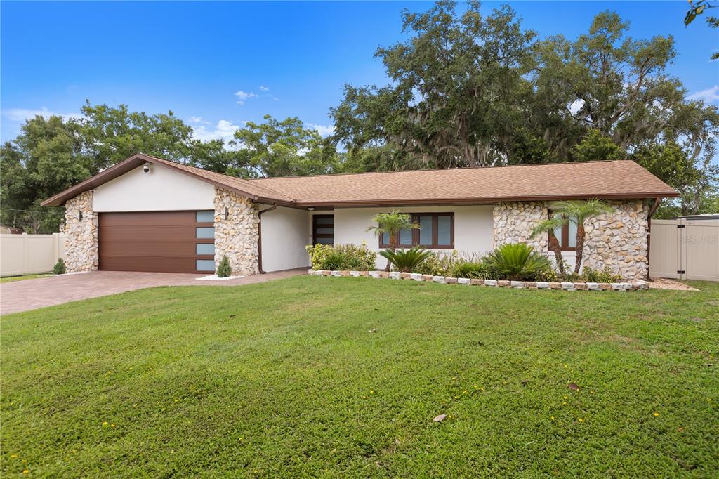 A single-story house with a stone facade, a brown garage door, and a grassy lawn — 1577 STARFISH STREET, KISSIMMEE, FL