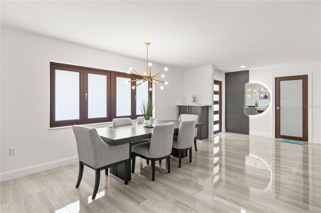 A modern dining room features a dark wood table, gray upholstered chairs, and a chandelier — 1577 STARFISH STREET, KISSIMMEE, FL