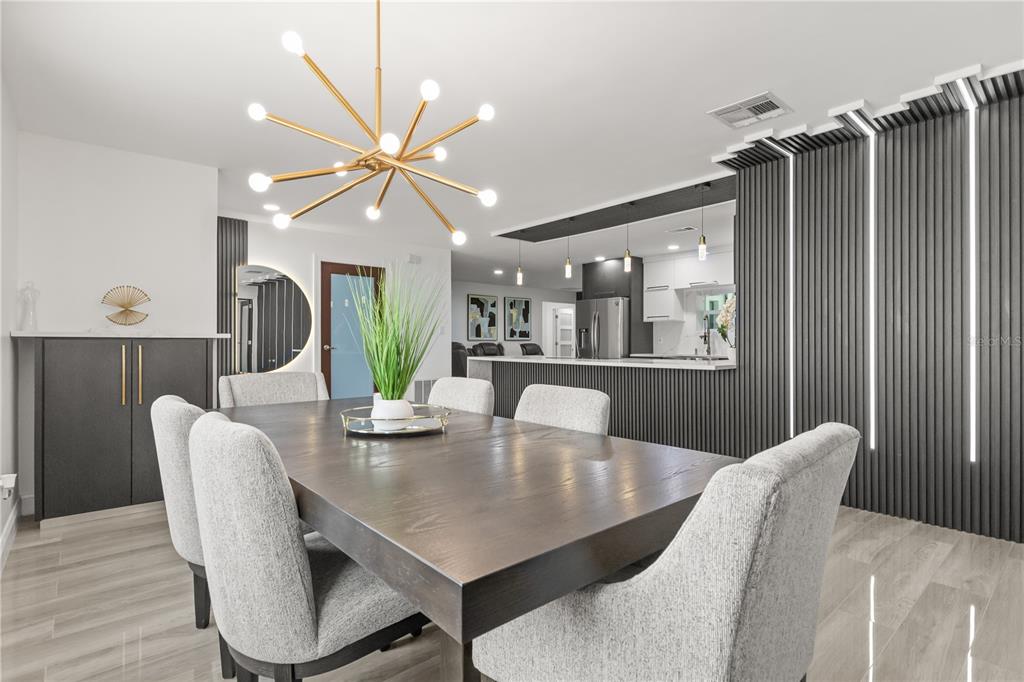 A dining room features a dark wood table, upholstered chairs, and a modern slat wall — 1577 STARFISH STREET, KISSIMMEE, FL