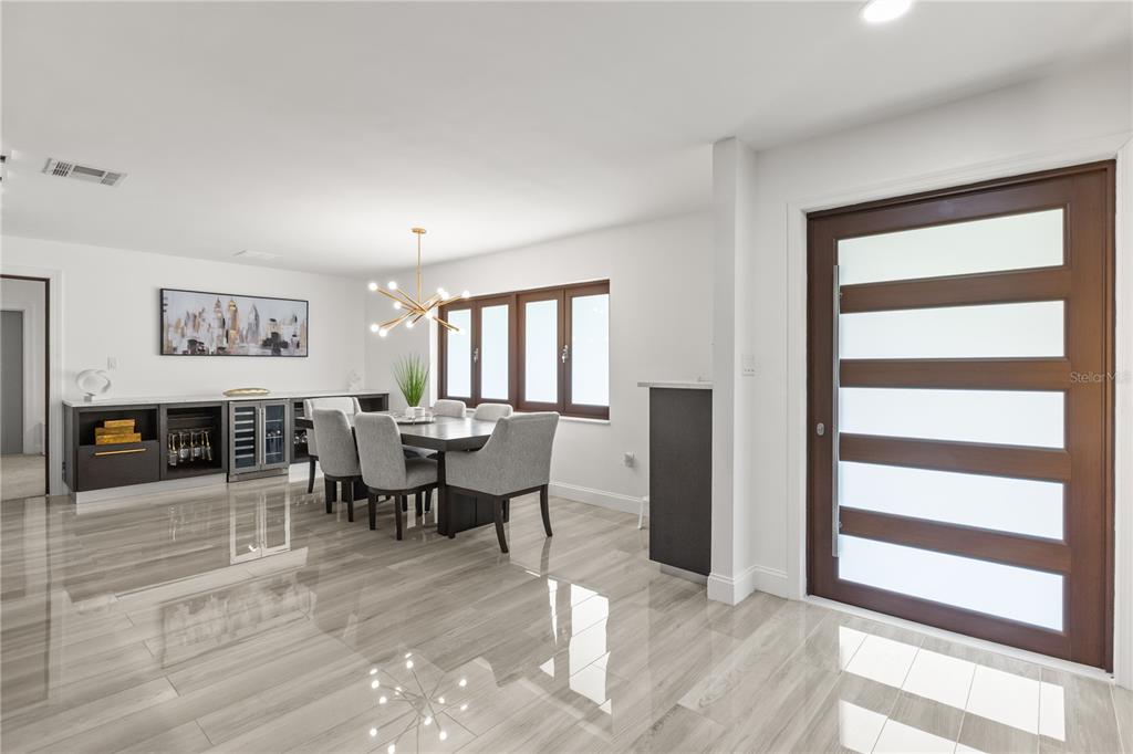 A dining area with a modern chandelier, gray upholstered chairs, and a built-in wet bar — 1577 STARFISH STREET, KISSIMMEE, FL