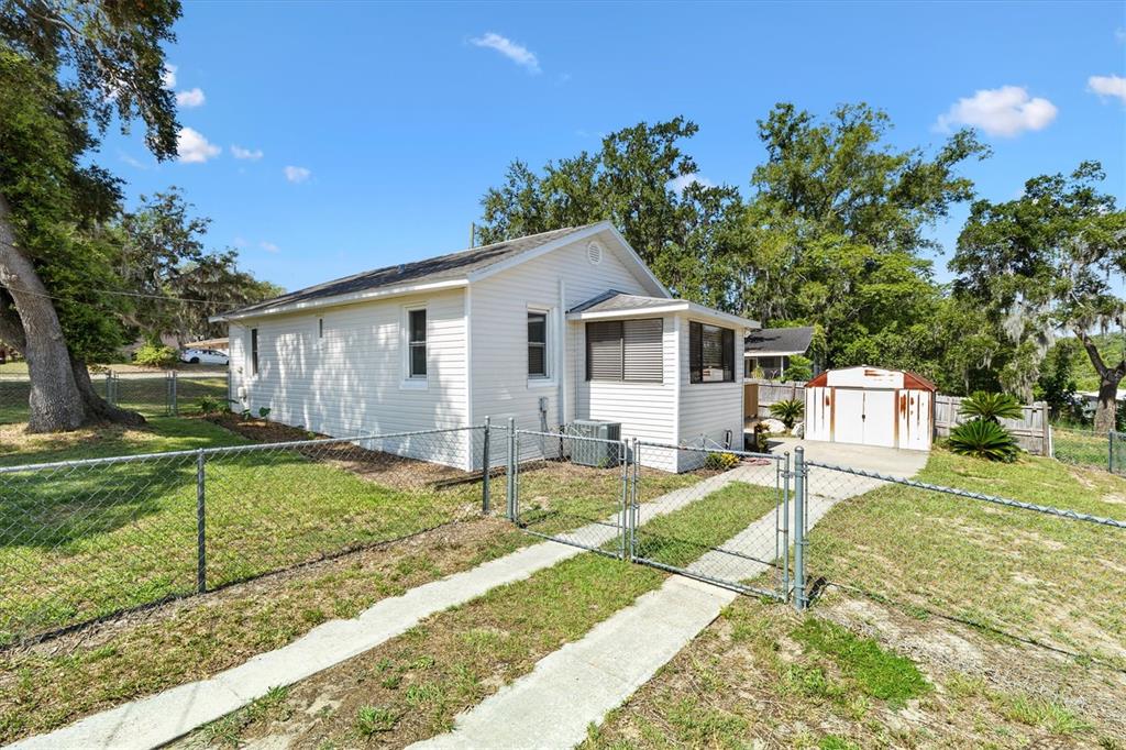 A white house with a chain-link fence and a detached shed in the backyard — 2000 SOUTH STREET, LEESBURG, FL