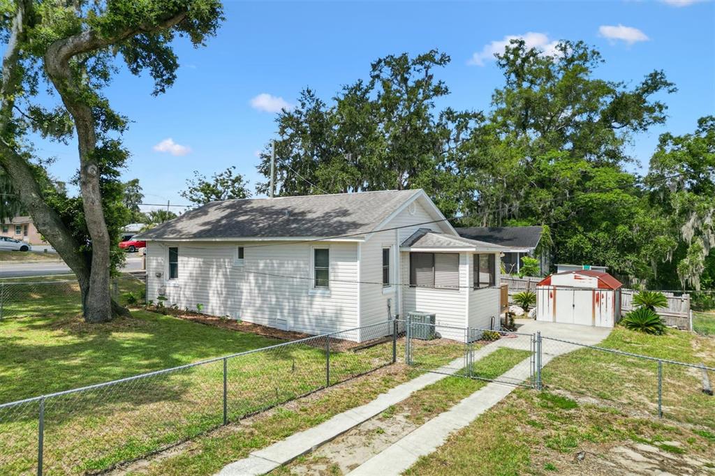 A white, single-story house with a fenced yard, a driveway, and a small storage shed — 2000 SOUTH STREET, LEESBURG, FL