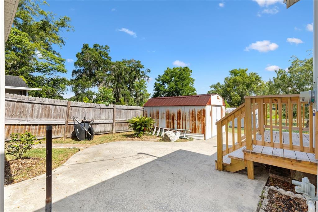 A backyard features a concrete patio, a wooden deck, a metal shed, and a wooden fence — 2000 SOUTH STREET, LEESBURG, FL