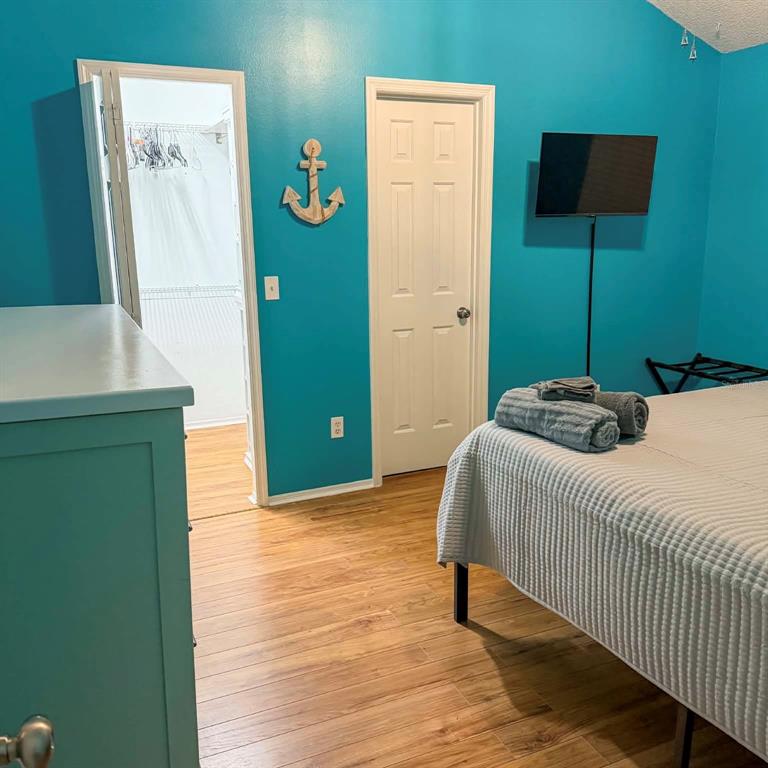 A bedroom with bright blue walls, wood-look flooring, a closet, and a bed — 1580 DORSET DRIVE, MOUNT DORA, FL