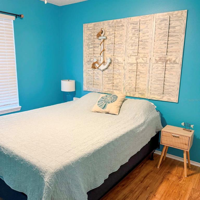 A bedroom features bright blue walls, a bed with a coastal-themed headboard, and wood flooring — 1580 DORSET DRIVE, MOUNT DORA, FL