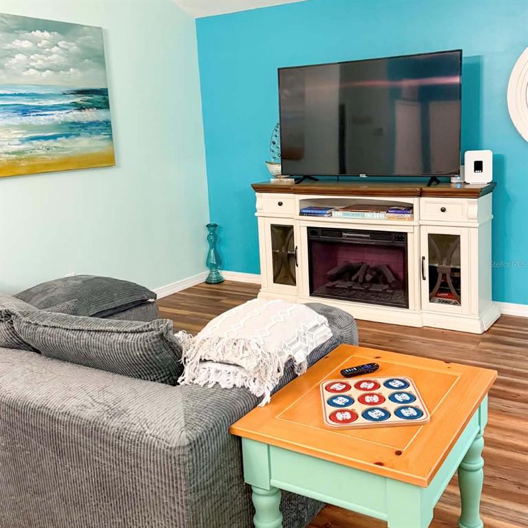 A living room features a gray sectional sofa, a television on a fireplace console, and a table — 1580 DORSET DRIVE, MOUNT DORA, FL