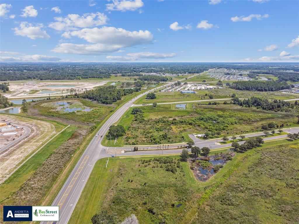 An aerial view shows a paved road intersection surrounded by undeveloped grassy land and wetlands — 0 N GALL BOULEVARD UNIT 1.08 Acres, ZEPHYRHILLS, FL