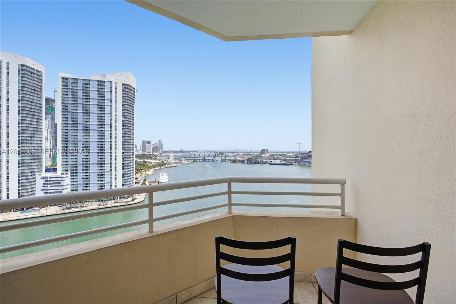 A balcony with two chairs overlooks a bay and high-rise buildings — 888 Brickell Key Dr # 2010, Miami FL 33131, MIAMI, FL