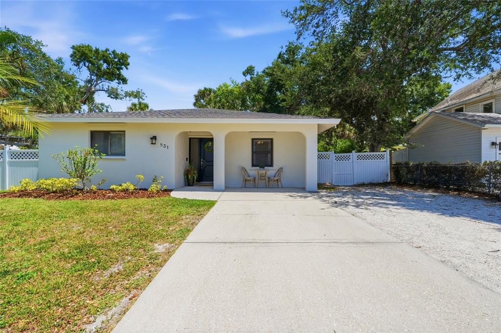 A single-story house with a concrete driveway, a covered front porch, and a white fence — 831 HIGHLAND STREET, SARASOTA, FL