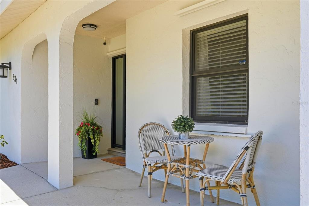 A covered front porch features a bistro set, a potted plant, and a glass-paneled door — 831 HIGHLAND STREET, SARASOTA, FL