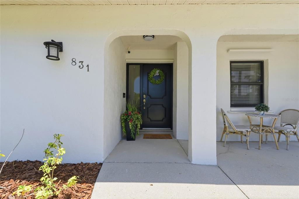The exterior of a house features a white stucco facade, a dark front door, and a porch — 831 HIGHLAND STREET, SARASOTA, FL