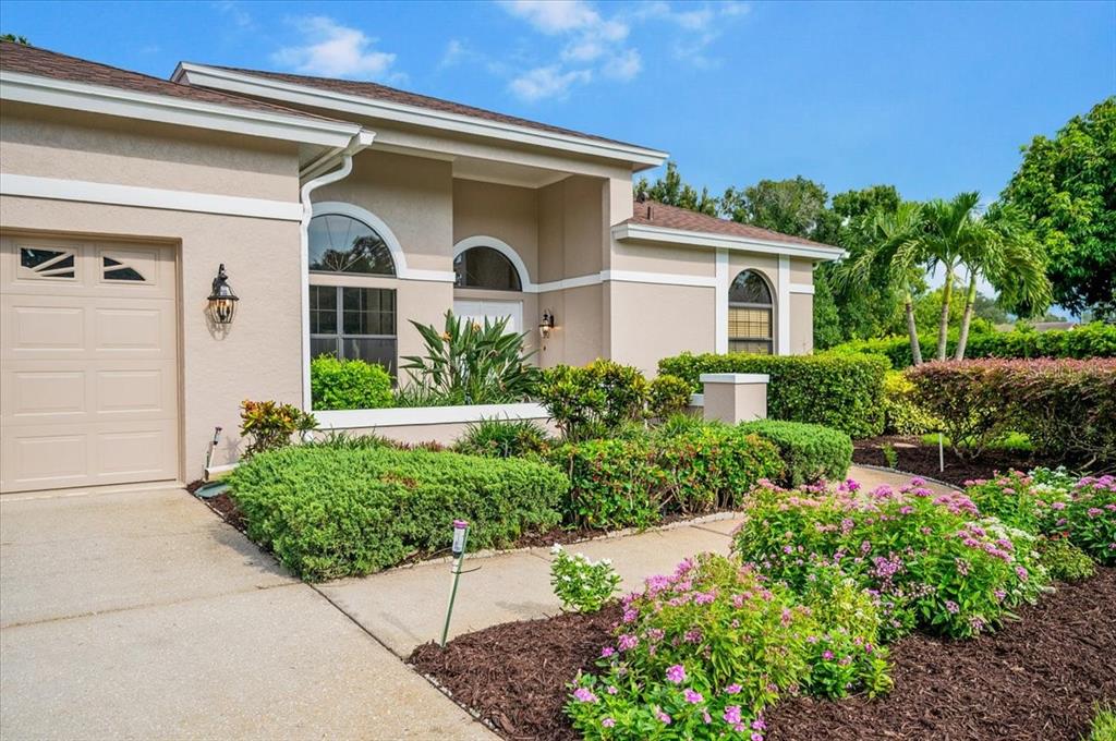 A beige single-story house features a garage, arched windows, and a landscaped front yard — 4451 CAICOS COURT, SARASOTA, FL