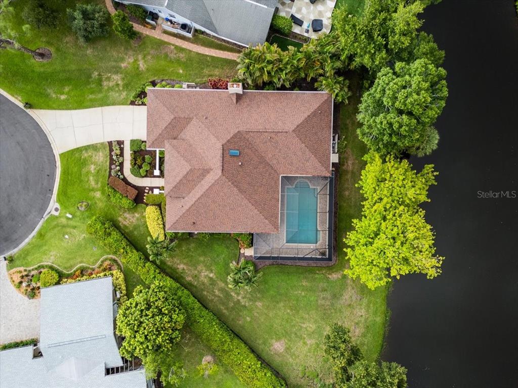 An aerial view shows a house with a brown roof, a screened pool, and landscaping — 4451 CAICOS COURT, SARASOTA, FL