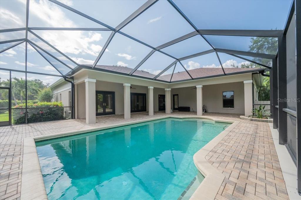 A swimming pool sits on a paved patio enclosed by a large screened-in lanai — 4451 CAICOS COURT, SARASOTA, FL