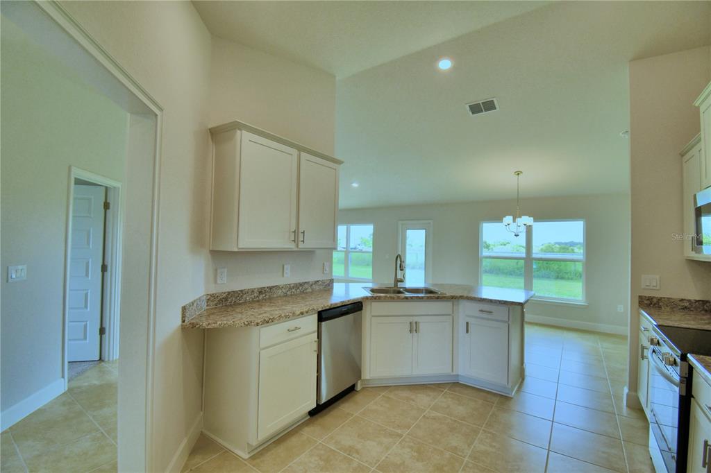 A kitchen with white cabinets, granite countertops, stainless steel appliances, and tile flooring — 4612 CALAMINT LANE, AUBURNDALE, FL