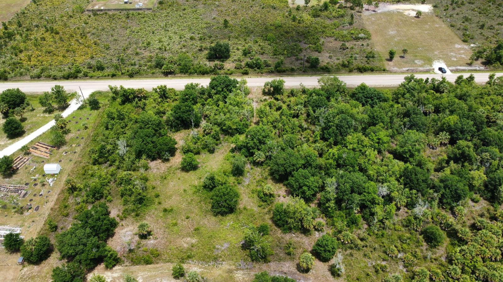 An aerial view shows a wooded, undeveloped lot bordered by a road and neighboring properties — 16436 NW 256th Street, Okeechobee FL 34972, OKEECHOBEE, FL