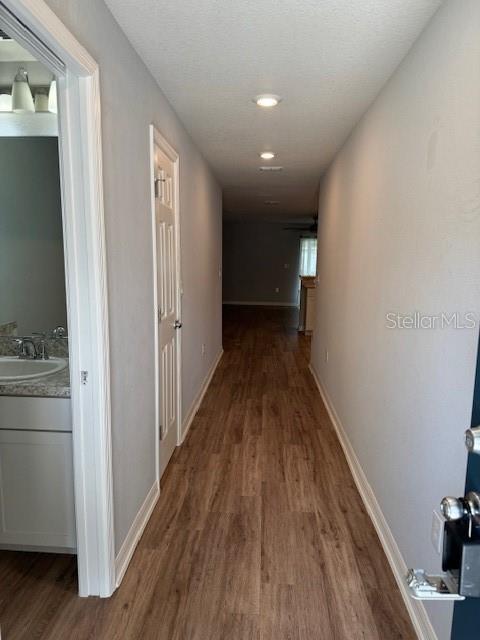 A hallway with wood-look flooring leads toward an open living area with a bathroom entrance — 3071 FIELDWOOD CIRCLE, ST CLOUD, FL