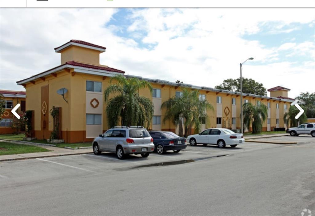 A multi-story yellow apartment building with a parking lot in the foreground — 728 RIDENHOUR CIRCLE UNIT 728, ORLANDO, FL