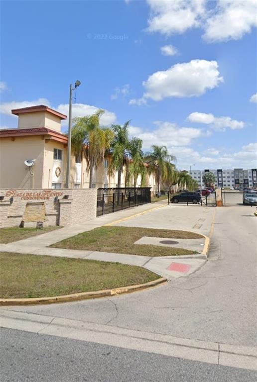 The exterior of a multi-story condominium complex with palm trees and a gated entrance — 728 RIDENHOUR CIRCLE UNIT 728, ORLANDO, FL
