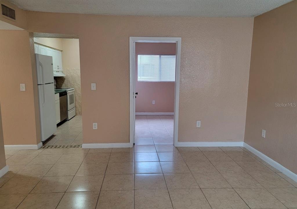 A tiled living area opens to a kitchen on the left and a bedroom beyond — 728 RIDENHOUR CIRCLE UNIT 728, ORLANDO, FL