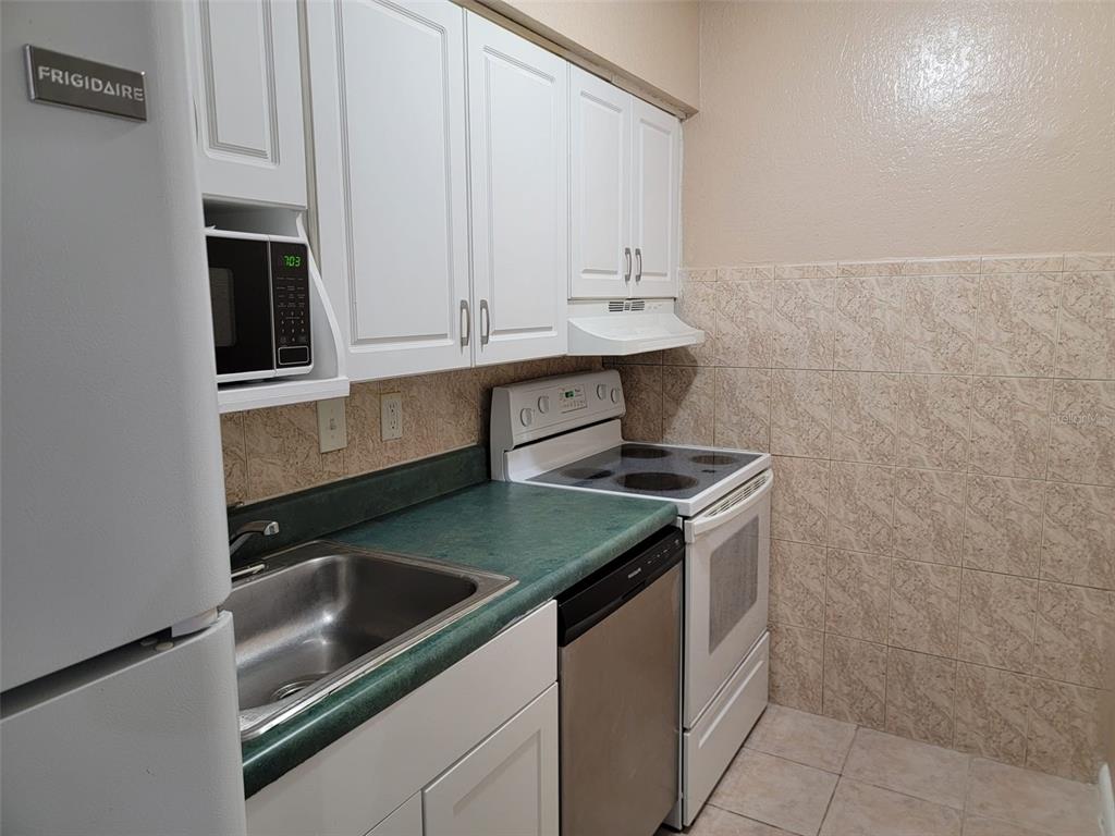 A kitchen features white cabinets, a green countertop, a stainless steel sink, and white appliances — 728 RIDENHOUR CIRCLE UNIT 728, ORLANDO, FL