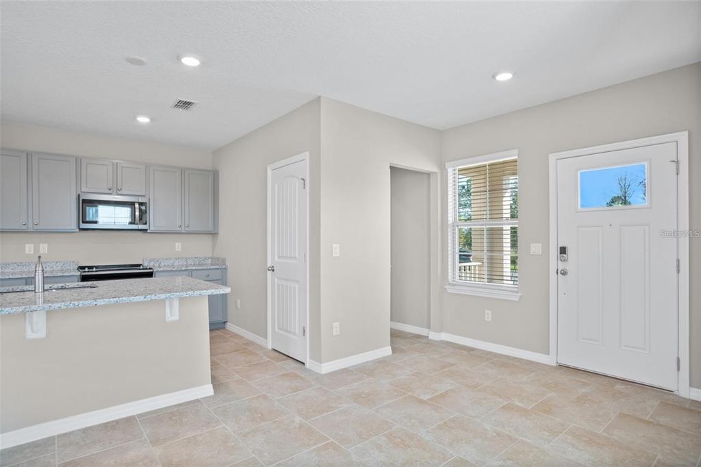 A kitchen with gray cabinets, granite countertops, and tile flooring next to an entryway — 11092 GREAT ROCK STREET, WINTER GARDEN, FL