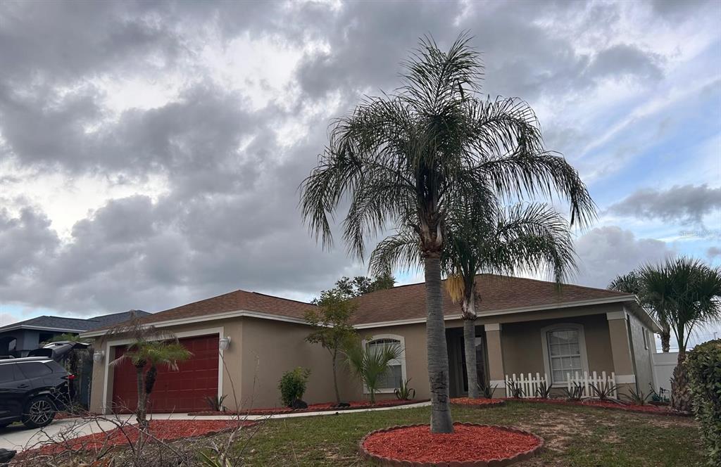 A single-story house with a red garage door and a palm tree in the front yard — 669 SIERRA CIRCLE, DAVENPORT, FL
