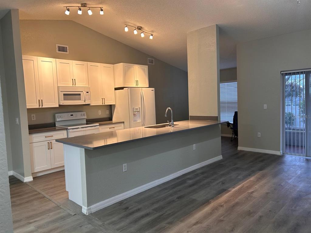 An open-concept kitchen with white cabinets and a breakfast bar overlooks a dining area — 669 SIERRA CIRCLE, DAVENPORT, FL