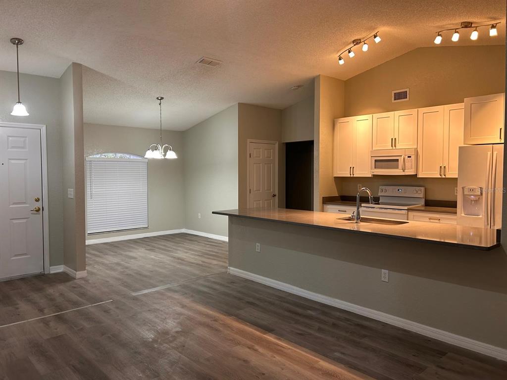 A kitchen with a breakfast bar and white appliances opens to a living area with sliding doors — 669 SIERRA CIRCLE, DAVENPORT, FL