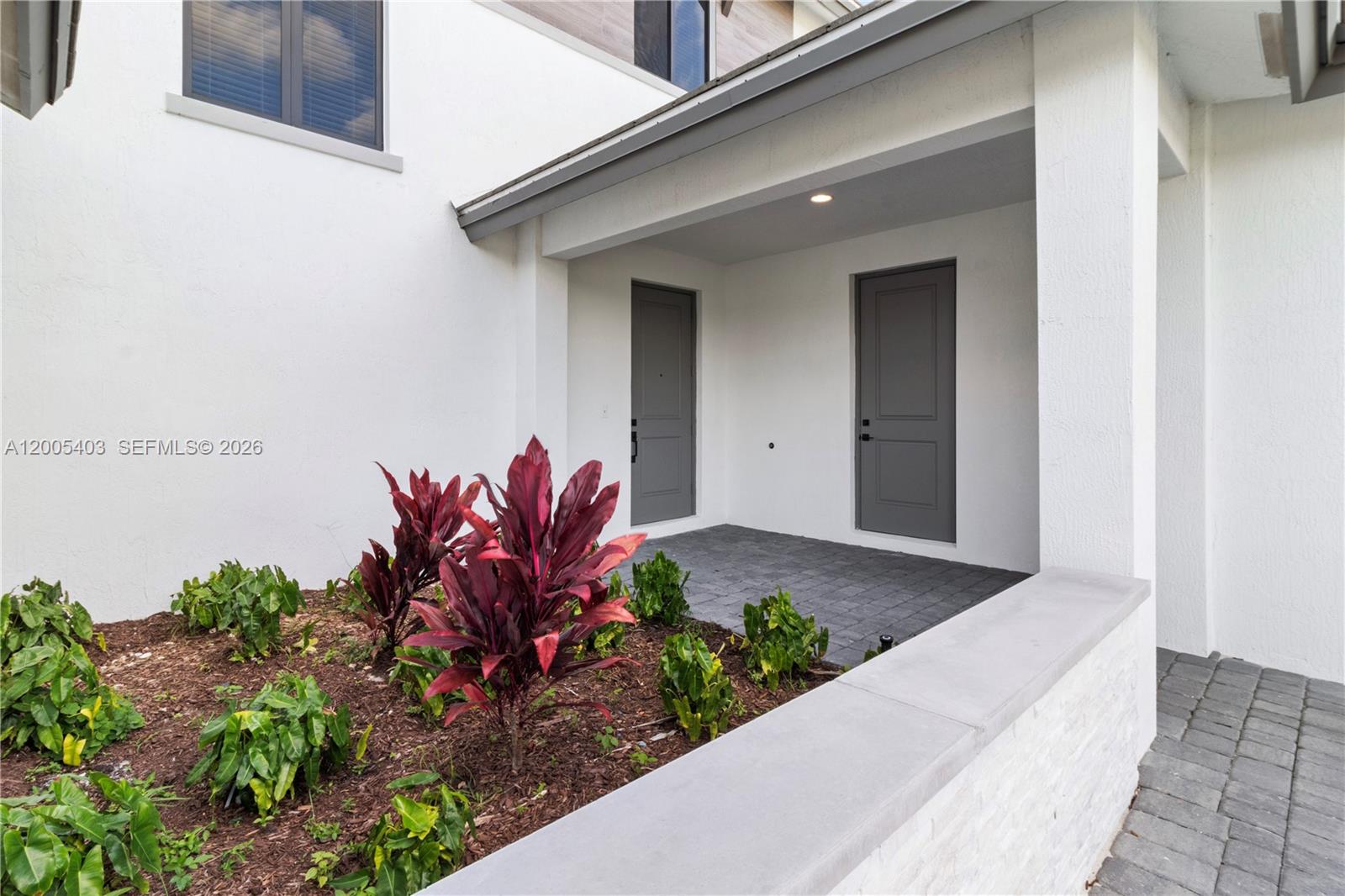 A covered entryway features two gray doors, a paved floor, and a landscaped garden bed — 2391 SW 123rd Ter, Davie FL 33325, DAVIE, FL