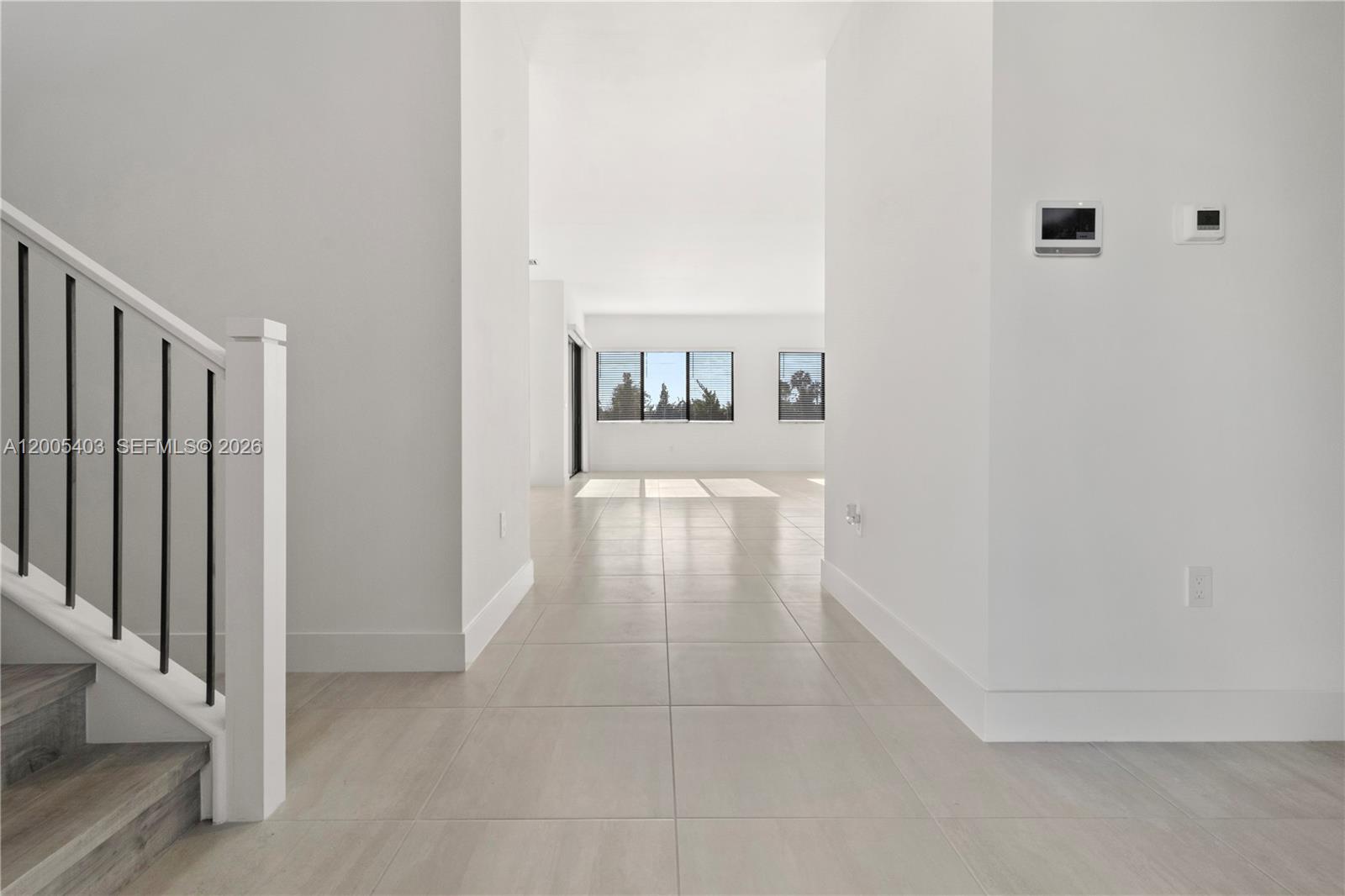 A bright, minimalist hallway with white walls and light tile flooring leads to a living area — 2391 SW 123rd Ter, Davie FL 33325, DAVIE, FL
