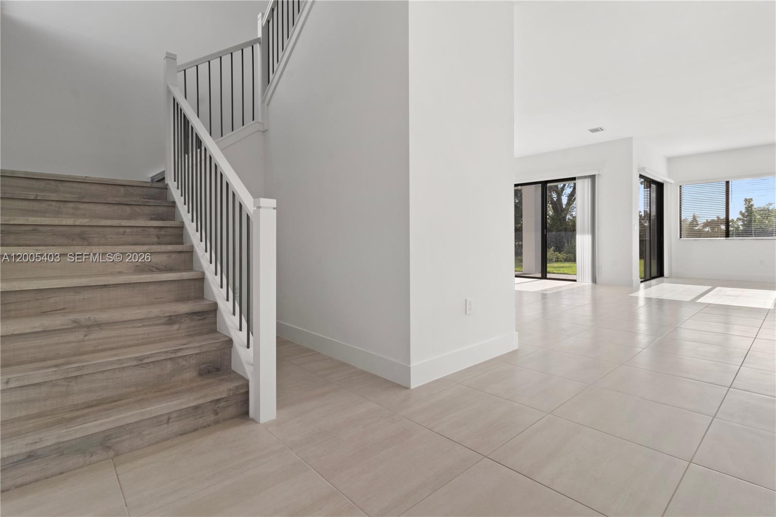 A staircase with wood-look treads and a white railing sits beside a tiled living area — 2391 SW 123rd Ter, Davie FL 33325, DAVIE, FL
