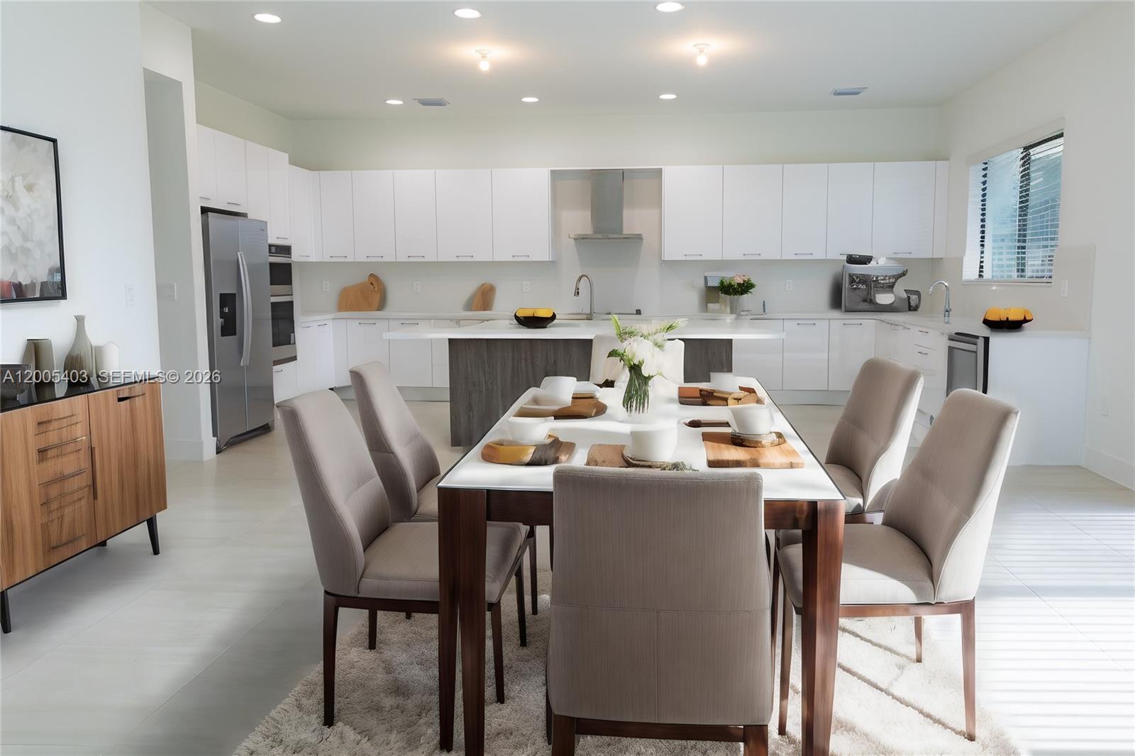 A modern kitchen features white cabinetry, a central island, and a dining table with chairs — 2391 SW 123rd Ter, Davie FL 33325, DAVIE, FL
