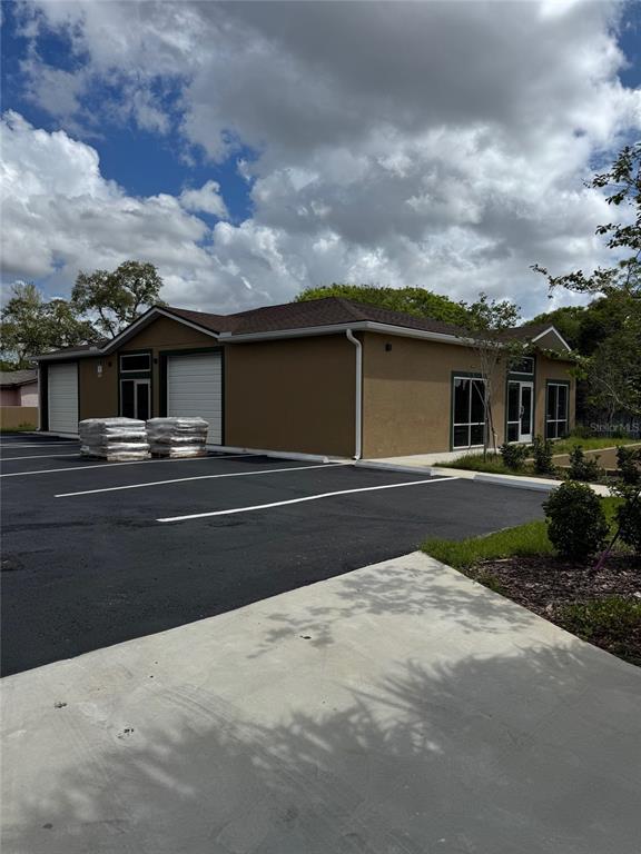 An exterior view of a tan commercial building with a parking lot and two garage doors — 6315 OLD WINTER GARDEN ROAD, ORLANDO, FL