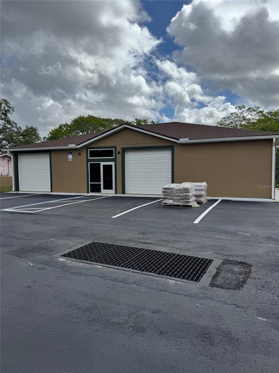 A tan commercial building with two garage doors and a central entrance in a parking lot — 6315 OLD WINTER GARDEN ROAD, ORLANDO, FL