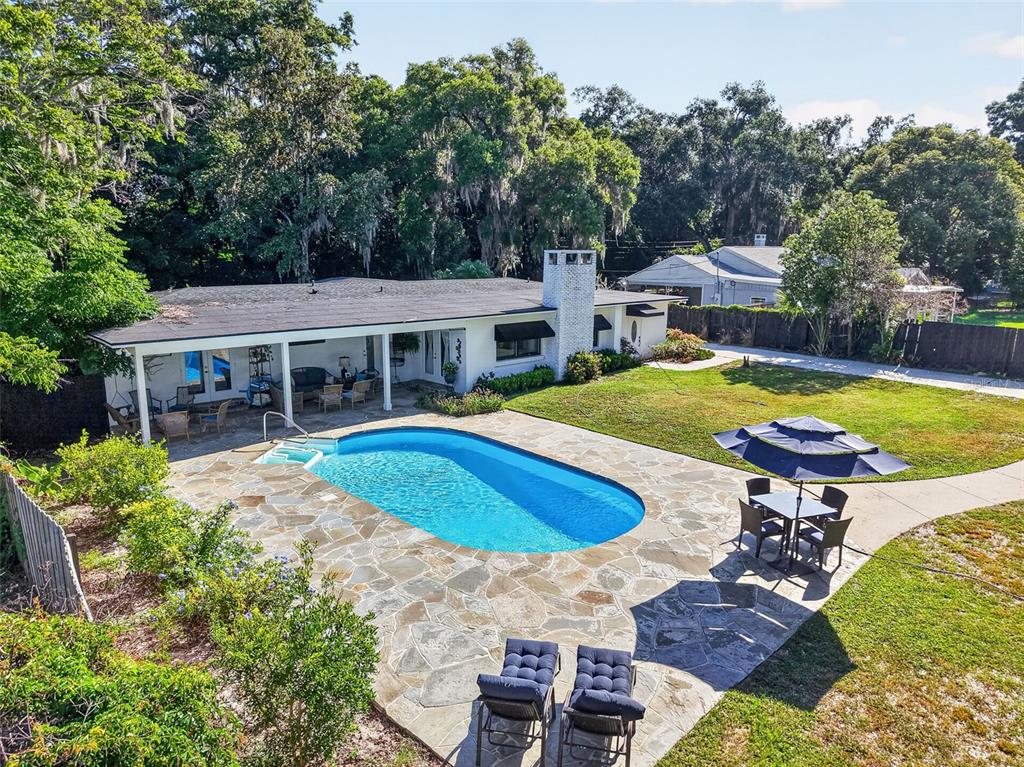 An aerial view of a backyard featuring a swimming pool, stone patio, and house exterior — 414 W 12TH AVENUE, MOUNT DORA, FL
