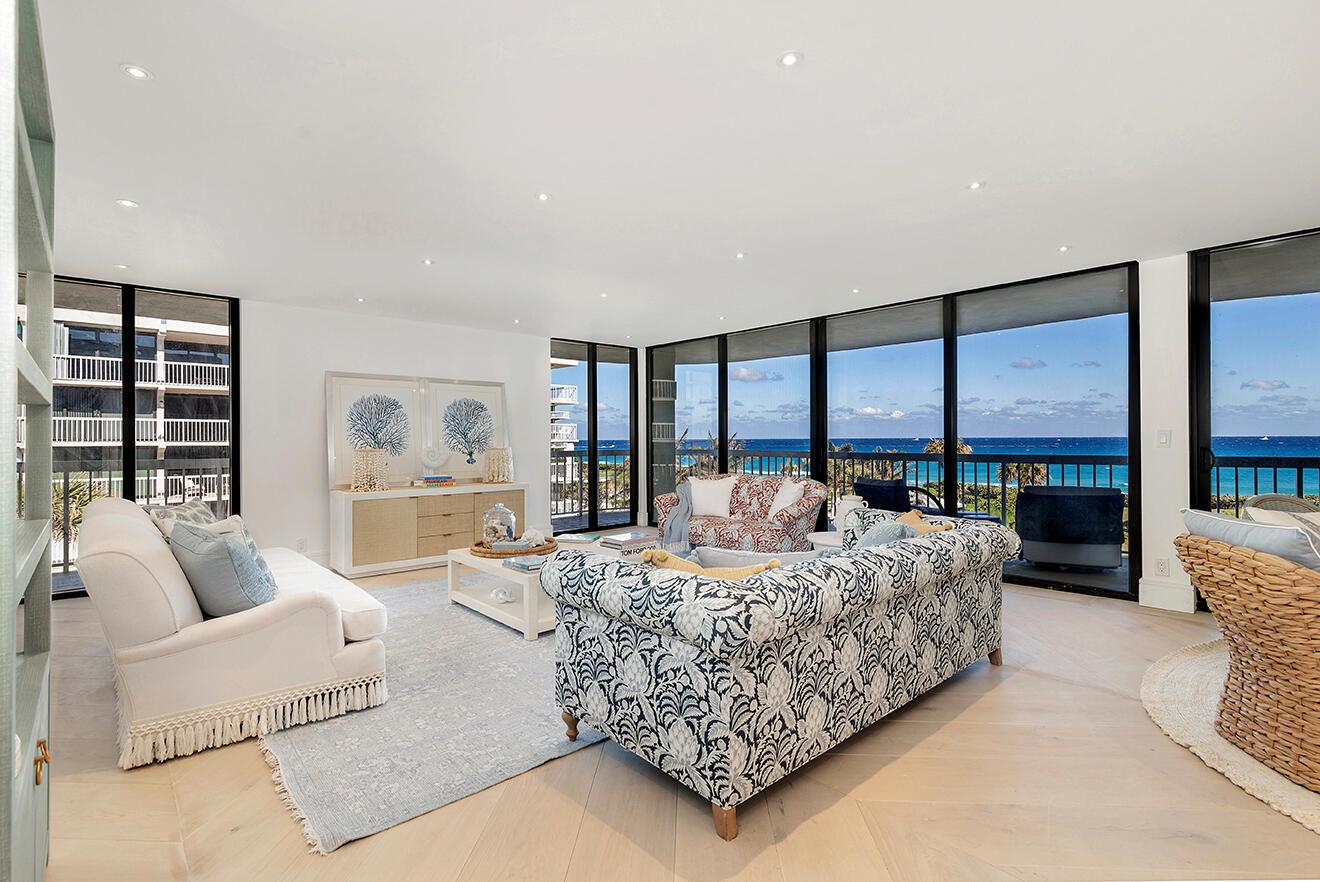 A bright living room features white sofas, patterned furniture, and floor-to-ceiling windows overlooking the ocean — 3300 S Ocean Boulevard # 305n, Palm Beach FL 33480, PALM BEACH, FL