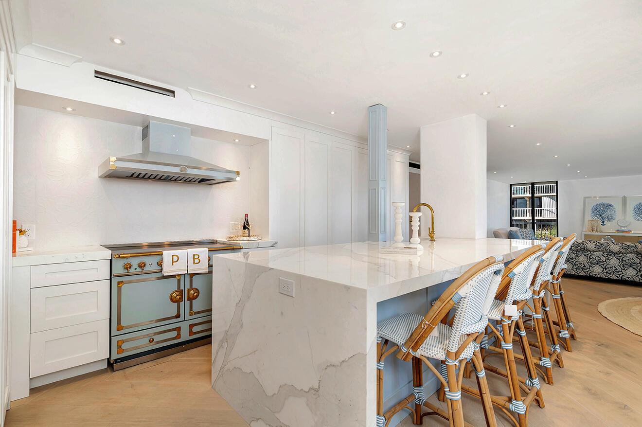 A kitchen features a light blue range, a marble waterfall island, and woven bar stools — 3300 S Ocean Boulevard # 305n, Palm Beach FL 33480, PALM BEACH, FL