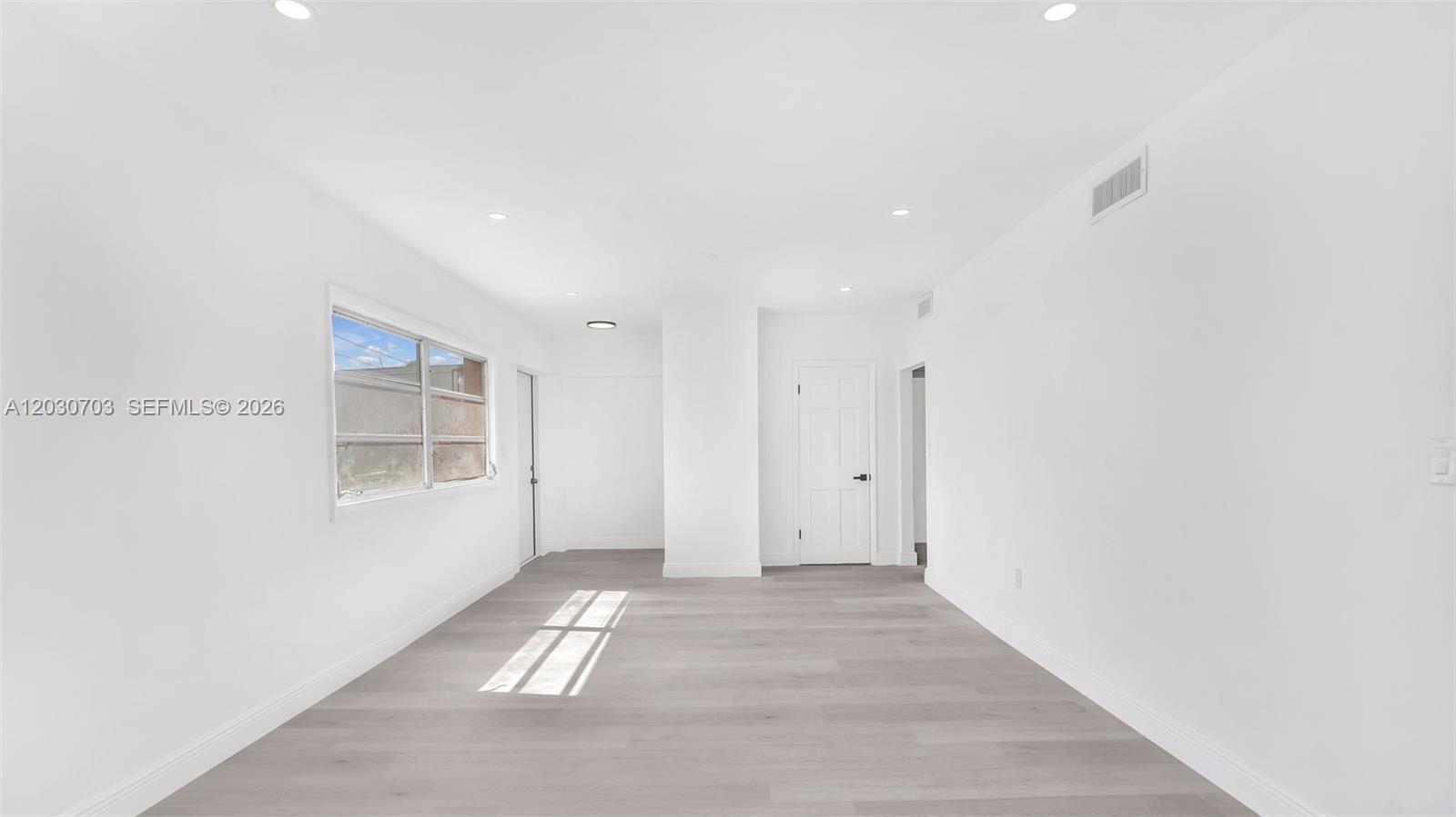 A bright, empty room features white walls, light-colored wood-look flooring, and a single window — 1365 NW 55th Ter # B, Miami FL 33142, MIAMI, FL
