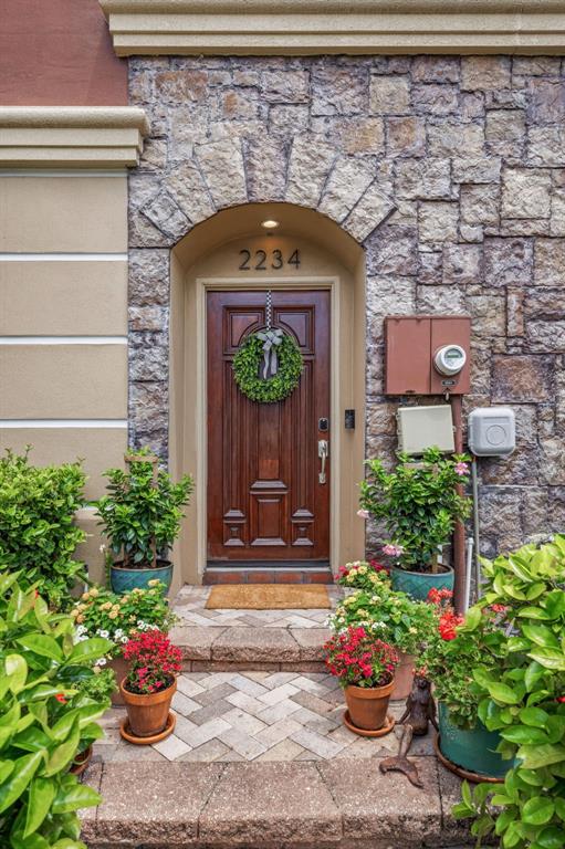 A front entrance features a wooden door, stone facade, and potted plants on a brick walkway — 2234 SOHO BAY CT, TAMPA, FL