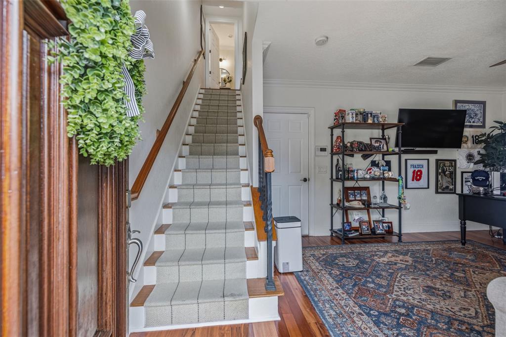 A staircase with a patterned runner leads to an upper floor beside a living area — 2234 SOHO BAY CT, TAMPA, FL