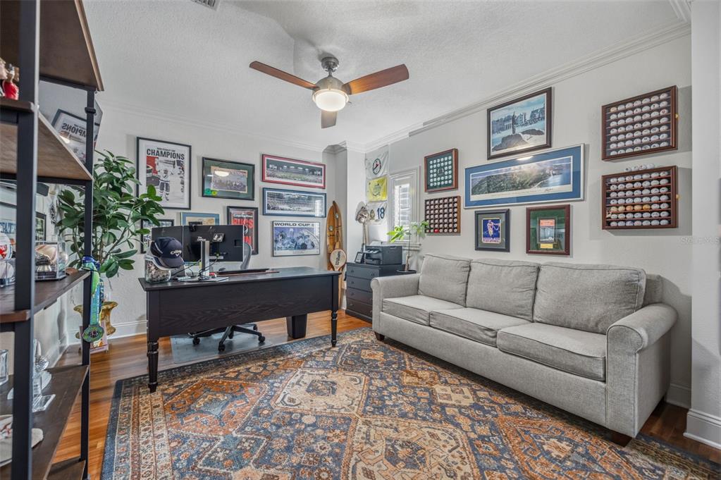 A home office features a desk, a gray sofa, a patterned rug, and wall-mounted memorabilia — 2234 SOHO BAY CT, TAMPA, FL