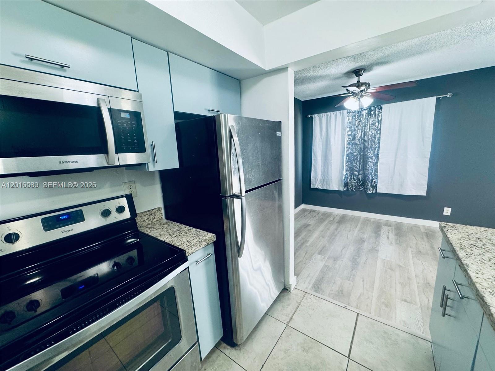 A kitchen with stainless steel appliances and light blue cabinets opens into a dining area — 5908 NW 21st St # A, Lauderhill FL 33313, LAUDERHILL, FL