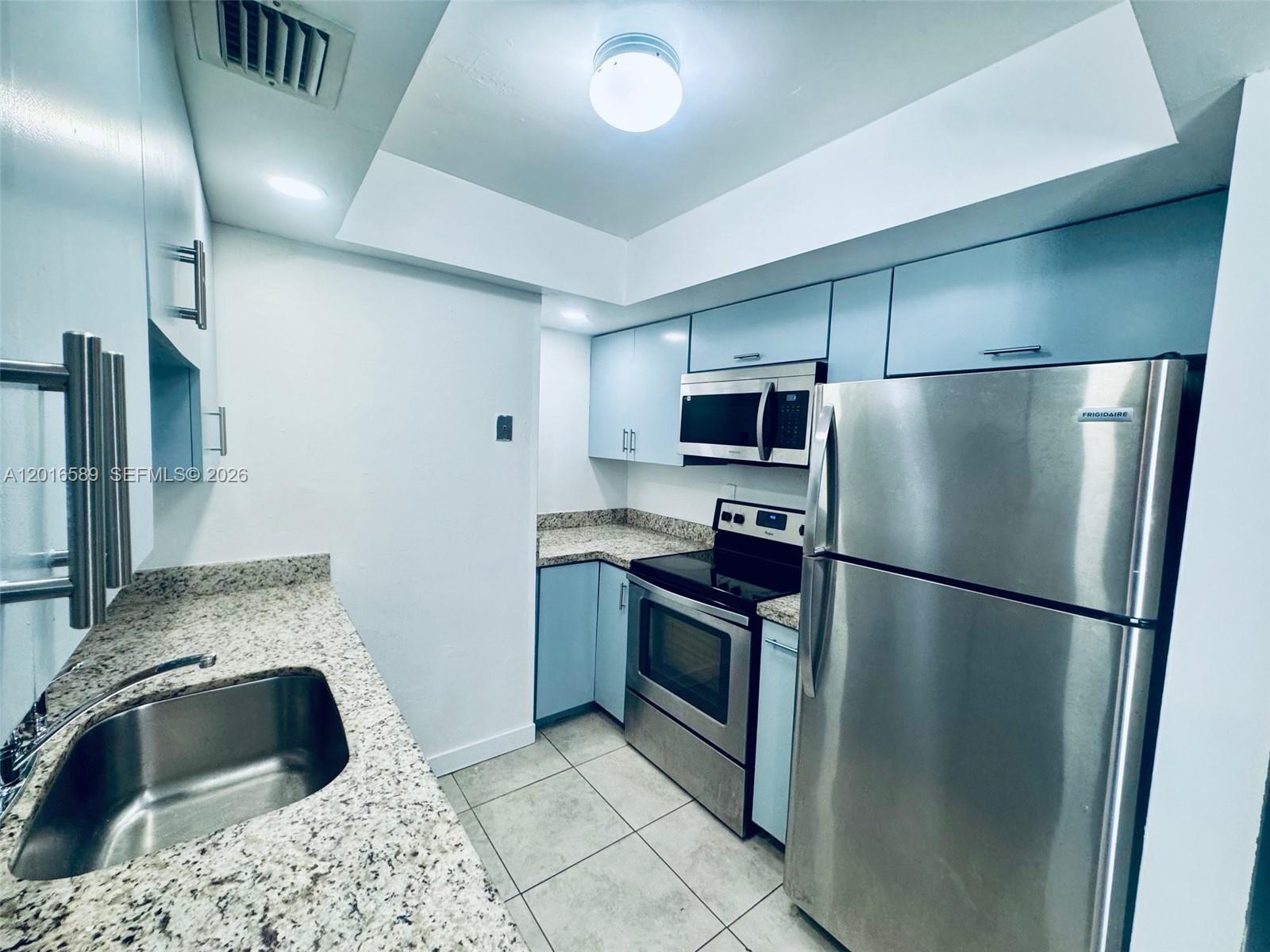 A kitchen features light blue cabinets, granite countertops, and stainless steel appliances — 5908 NW 21st St # A, Lauderhill FL 33313, LAUDERHILL, FL