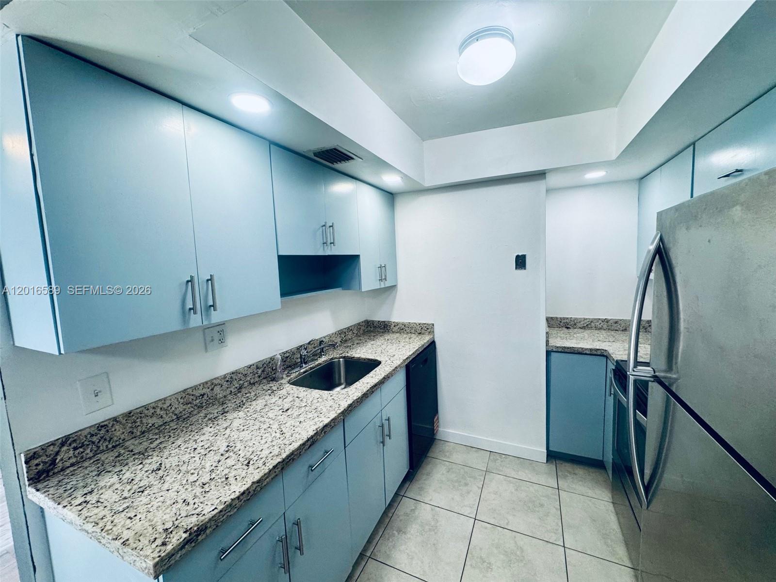 A kitchen features light blue cabinets, granite countertops, stainless steel appliances, and tile flooring — 5908 NW 21st St # A, Lauderhill FL 33313, LAUDERHILL, FL