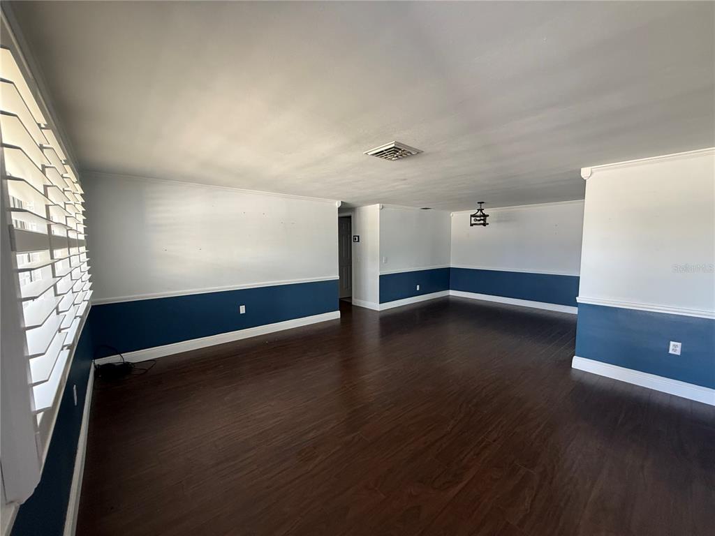 An empty room with dark wood flooring, white walls, and blue wainscoting — 5240 SCHOOL ROAD, NEW PORT RICHEY, FL